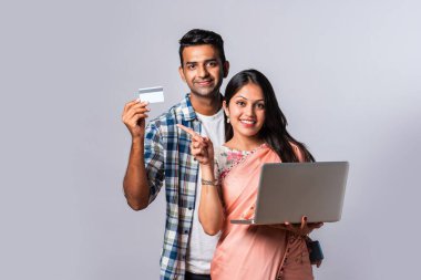 Hintli evli genç çift dizüstü bilgisayar kullanıyor.