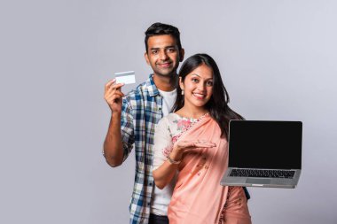 Hintli evli genç çift dizüstü bilgisayar kullanıyor.