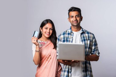 Hintli evli genç çift dizüstü bilgisayar kullanıyor.