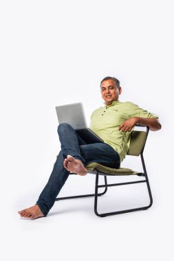 Orta yaşlı Asyalı yakışıklı adam dizüstü bilgisayar kullanıyor, ayakta duruyor ya da beyaz arka planda oturuyor.