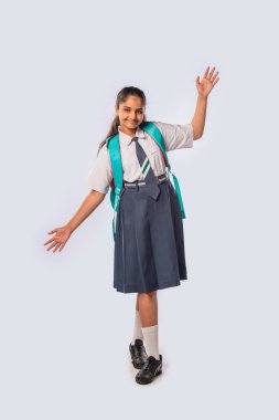 Hintli Asyalı kız okul üniforması giyiyor ve sırt çantasıyla ayakta duruyor.
