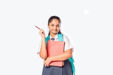 Okul üniformalı Hintli kız elinde kitaplarla beyazlara karşı duruyor.