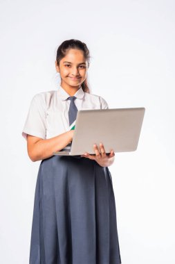 Küçük Hintli Asyalı kız dizüstü bilgisayarda çalışırken beyaz arka planda tek başına duruyor.