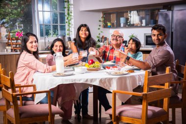 Mutlu Asyalı kuşak Hintli aile evde birlikte yemek yiyor..