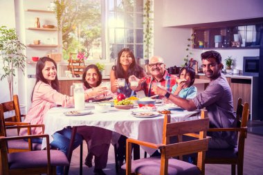 Mutlu Asyalı kuşak Hintli aile evde birlikte yemek yiyor..