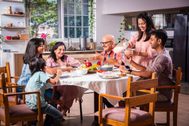 Mutlu Asyalı kuşak Hintli aile evde birlikte yemek yiyor..