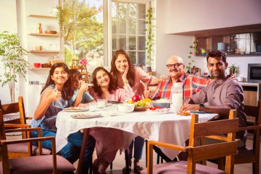 Mutlu Asyalı kuşak Hintli aile evde birlikte yemek yiyor..