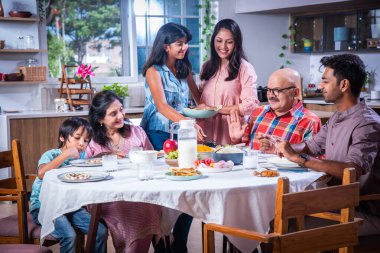 Mutlu Asyalı kuşak Hintli aile evde birlikte yemek yiyor..