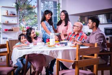 Mutlu Asyalı kuşak Hintli aile evde birlikte yemek yiyor..