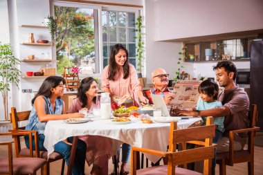 Mutlu Asyalı kuşak Hintli aile evde birlikte yemek yiyor..