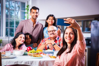 Hintli altı kişilik Asyalı aile öğle yemeği yiyor ve evde selfie çekiyorlar.