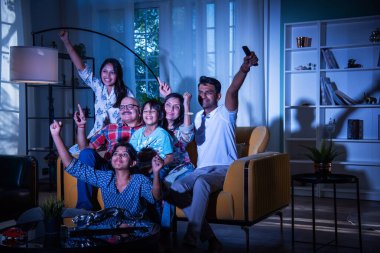 Mutlu Hintli Asyalı çok nesilli aile evde kanepede otururken televizyon ya da televizyon izliyor.