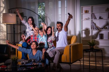 Mutlu Hintli Asyalı çok nesilli aile evde kanepede otururken televizyon ya da televizyon izliyor.