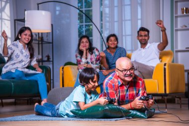 Hintli büyükbaba evde torunlarıyla video oyunu oynuyor.