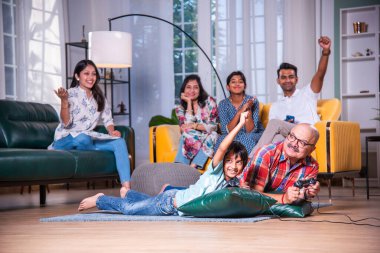 Hintli büyükbaba evde torunlarıyla video oyunu oynuyor.