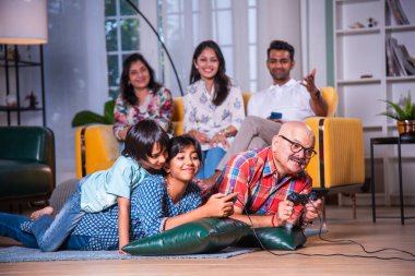 Hintli büyükbaba evde torunlarıyla video oyunu oynuyor.