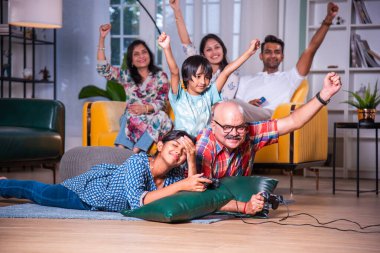 Hintli büyükbaba evde torunlarıyla video oyunu oynuyor.