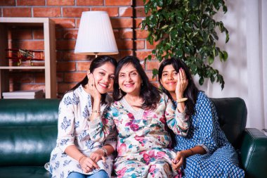 Mutlu Hintli Asyalıların portresi. Üç nesildir kanepede oturan büyükanne, kız ve kız torun.