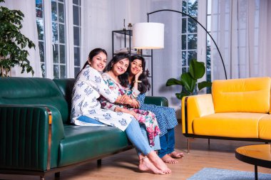 Mutlu Hintli Asyalıların portresi. Üç nesildir kanepede oturan büyükanne, kız ve kız torun.