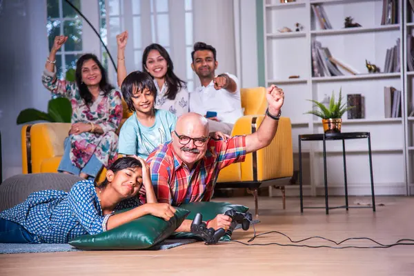 Hintli büyükbaba evde torunlarıyla video oyunu oynuyor.