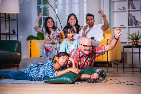 Hintli büyükbaba evde torunlarıyla video oyunu oynuyor.