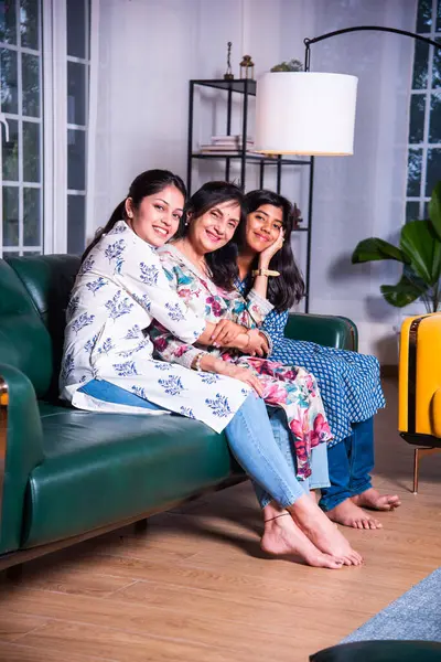 Mutlu Hintli Asyalıların portresi. Üç nesildir kanepede oturan büyükanne, kız ve kız torun.