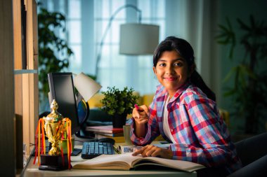 Hintli Asyalı genç kız evde kişisel bilgisayar, ev eğitimi konseptini kullanarak okuyor.