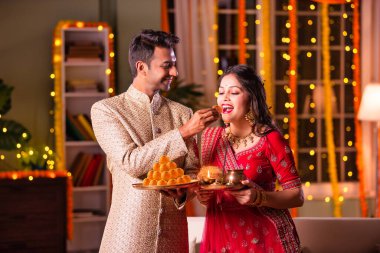 Geleneksel Hintli genç çift Diwali 'de ya da yıldönümünde tatlı laddu yiyorlar.