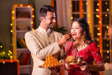 Geleneksel Hintli genç çift Diwali 'de ya da yıldönümünde tatlı laddu yiyorlar.
