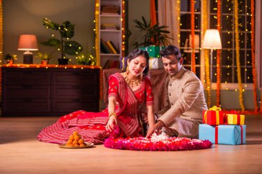 Hintli genç çift, Diwali Festivali 'nde çiçek Rangoli' si yapıyorlar.