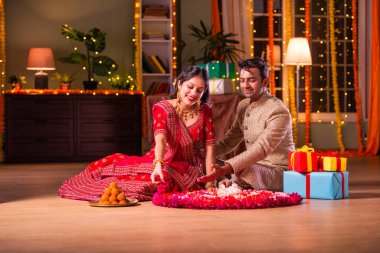 Hintli genç çift, Diwali Festivali 'nde çiçek Rangoli' si yapıyorlar.