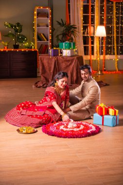 Hintli genç çift, Diwali Festivali 'nde çiçek Rangoli' si yapıyorlar.