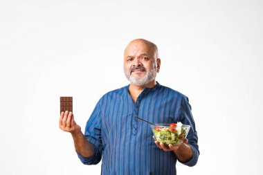 60 'lı yaşlarda emekli Hintli yaşlı adam sağlıklı yeşil sebze salatası yiyor.