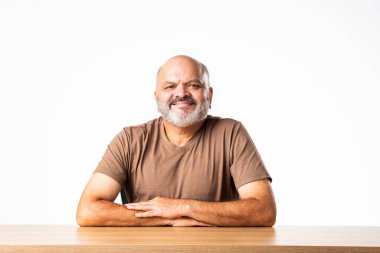 Yakışıklı Hintli emekli yaşlı bir adamın portresi beyaz duvara yaslanmış, farklı pozlar ve ifadelerle.