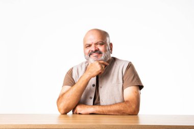 Yakışıklı Hintli emekli yaşlı bir adamın portresi beyaz duvara yaslanmış, farklı pozlar ve ifadelerle.