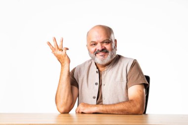 Yakışıklı Hintli emekli yaşlı bir adamın portresi beyaz duvara yaslanmış, farklı pozlar ve ifadelerle.