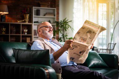 Evde gazete okuyan kendini ifade eden Hintli kıdemli yaşlı adam.