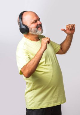 Hint asıllı emekli yaşlı adam müzik dinliyor, dans ediyor, kulaklık takıyor, beyaz arka planda izole edilmiş..