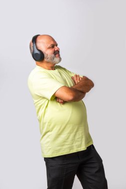 Hint asıllı emekli yaşlı adam müzik dinliyor, dans ediyor, kulaklık takıyor, beyaz arka planda izole edilmiş..
