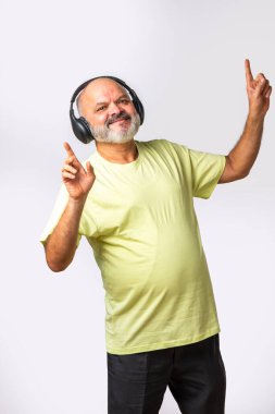 Hint asıllı emekli yaşlı adam müzik dinliyor, dans ediyor, kulaklık takıyor, beyaz arka planda izole edilmiş..