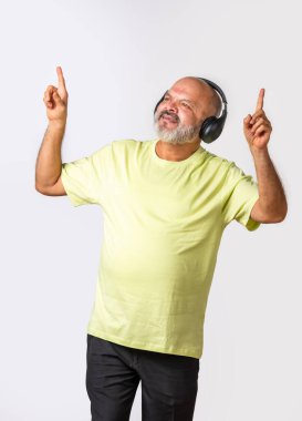 Hint asıllı emekli yaşlı adam müzik dinliyor, dans ediyor, kulaklık takıyor, beyaz arka planda izole edilmiş..