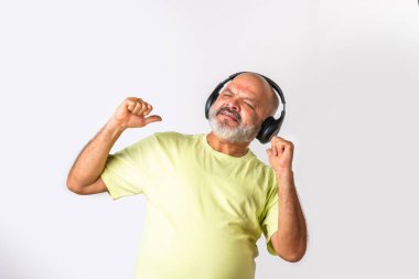 Hint asıllı emekli yaşlı adam müzik dinliyor, dans ediyor, kulaklık takıyor, beyaz arka planda izole edilmiş..