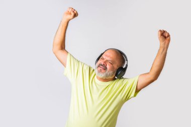 Hint asıllı emekli yaşlı adam müzik dinliyor, dans ediyor, kulaklık takıyor, beyaz arka planda izole edilmiş..