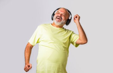 Hint asıllı emekli yaşlı adam müzik dinliyor, dans ediyor, kulaklık takıyor, beyaz arka planda izole edilmiş..