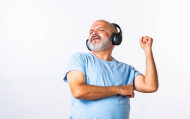 Hint asıllı emekli yaşlı adam müzik dinliyor, dans ediyor, kulaklık takıyor, beyaz arka planda izole edilmiş..