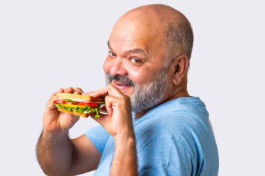 Asyalı yaşlı yaşlı adam lezzetli sebzeli sandviç yiyor, izole edilmiş.