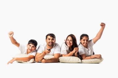 Dört kişilik mutlu Asyalı aile beyaz zemin üzerinde tek başına yatarken televizyon seyrediyor.