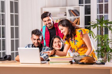 Hintli dört üniversite öğrencisi ya da üniversite öğrencileri masada çalışmak için dizüstü bilgisayar kullanıyor