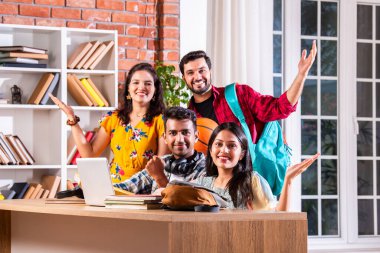 Hintli dört üniversite öğrencisi ya da üniversite öğrencileri masada çalışmak için dizüstü bilgisayar kullanıyor