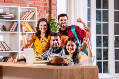 Hintli dört üniversite öğrencisi ya da üniversite öğrencileri masada çalışmak için dizüstü bilgisayar kullanıyor